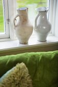 White ceramic jugs on a window sill