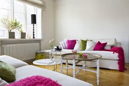 A white-painted living room with an oriental side table and a sofa in front of a window