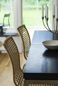 Wicker chairs and candelabra on a table in front of a French window