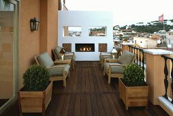 Crackling fire in a fireplace on a roof terrace with wood floor and seating with gray upholstery