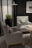Armchairs upholstered in gray in the corner of a living room with a closed Venetian blind with ambient lighting