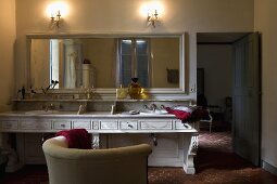 Country style bathroom -- ambient wall lighting above a long vanity with a mirror