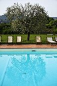 Reflection in a turquoise pool with lounge chairs on a terracotta tile