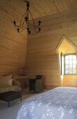 Bedroom in an attic with bright wood paneling on the walls and ceiling
