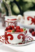 Gemusterte Tasse mit roten Beeren und Kirschen