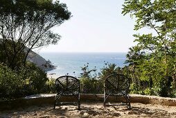 Terrace with black rattan chairs and a view of the sea
