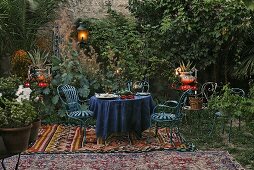 Romantisches Picknick - blaue Gartenmöbel auf orientalischer Decke mit Laterne und Windlichter