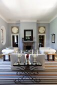 Striped carpet in a living room with a fireplace and metal side table with candles in decorative glass containers in front of a sofa