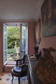 Living room with antiques and a view through open windows into the garden