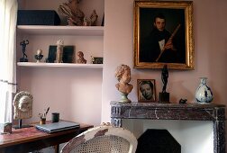 Mantelpiece in front of a pink wall and work area with built-in shelves