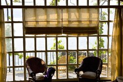 Sonniger Tag- Korbstühle vor Sprossenfenster mit Blick auf Terrasse und den See