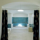A bathroom with a vaulted ceiling - a view through an open curtain onto a bath in a niche with blue wall tiles