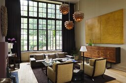 An art deco style armchair and a designer sideboard in front of studio windows with black frames