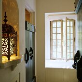 A hallway in a rustic country house - oriental lanterns in a wall niche and an open transom window