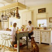 A family and a dog sitting at a kitchen island in the kitchen of a country house