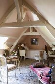 A bedroom in a rustic converted attic with wooden beams, antique chairs and a chaise longue