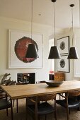 Black, retro-style metal pendant lamps above a wooden table and black upholstered wooden chairs