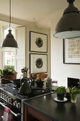 Metal lampshades above a kitchen counter and a cooker in an open plan kitchen in a country house