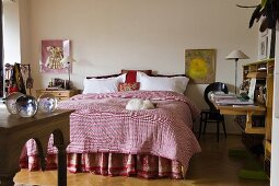 Schlafraum mit rosa Plaid auf dem Doppelbett und Sekretär an Wand