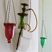 A water pipe in a white stone niche with coloured tea light holders hanging on either side