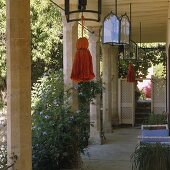 A terrace with stone pillar and lanterns with coloured tasssels hanging from the ceiling