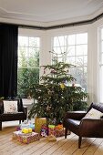 Ledersessel neben geschmücktem Weihnachtsbaum mit Geschenken im Erker eines Wohnraums