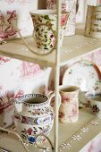 Porcelain crockery on an antique metal shelf standing against a wall