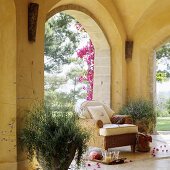 A cool refreshing drink next to a wicker chair and a plant pot in a yellow painted terrace