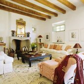 A white-painted fireplace room with a wood beamed ceiling and a sofa with a black coffee table