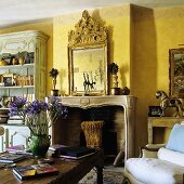 A yellow-painted living room with a fireplace and a chimney breast with a framed picture above the mantelpiece