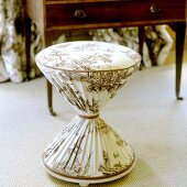 A diabolo-shaped stool with a patterned fabric cover