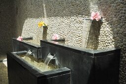 A spa pool against a pebble-dashed wall with water spouts