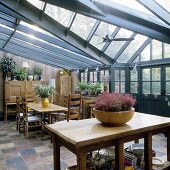 A rustic kitchen table and dining area in a conservatory with a grey steel structure