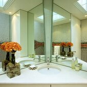 A mirrored cabinet in a bathroom - a corner wash basin with a white stone surface