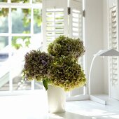 Blumen in Vase auf weisser Fensterbank