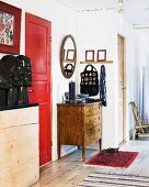 Wohnungsflur mit roter Tür und Holzkommoden