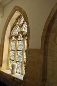 A Gothic pointed arch with stain glass and a sculpture on the window sill