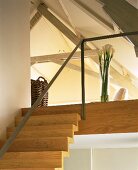 A flight of wooden stairs with a minimalistic banister and a gallery into an open attic room