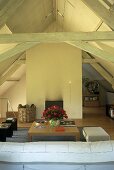A living room in a converted attic with a fireplace and wooden beams