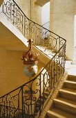 An elegant stairway - stairs with a wrought iron banister and an antique pendent lamp