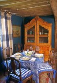 A meal in a country house - an antique cabinet against a blue wall in a room with a wood beam ceiling
