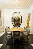 A wooden table with grey chairs in front of a white painted brick wall with a mirror hung on it