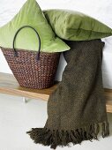 Green pillows in a basket and throw blanket on a board