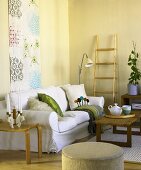 Weisses Sofa vor Wandbehang mit Couchtisch aus Holz und Beistelltisch