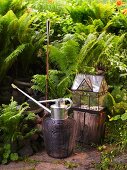 Watering can and torch next to a mini-greenhouse in the garden
