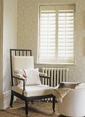 Corner of room in neutral colours with  shutters and a chair with a radiator