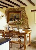 Dining room with a wooden table and chairs, artwork on an exposed stone wall.