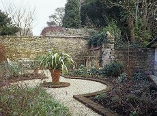 Walled garden with a pot plant central to a gravel path.