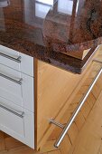 Arbeitsplatte aus Granit und Edelstahlfussleiste auf Küchenmöbel