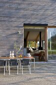 Table and chairs on decked terrace outside modern house